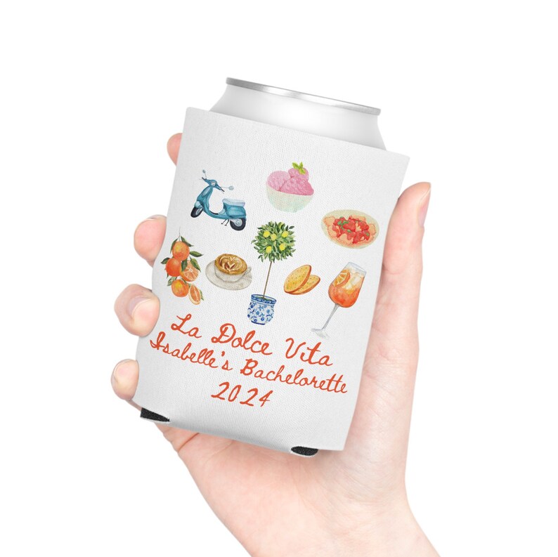 May include: White can cooler with a design of Italian-themed illustrations, including a scooter, a lemon tree, a glass of Aperol Spritz, and a plate of fruit. The text "La Dolce Vita Isabelle's Bachelorette 2024" is printed on the cooler.