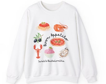 Peut inclure: Sweat-shirt blanc avec un motif graphique de nourriture italienne, notamment des pizzas, des pâtes, des crevettes et de la glace. Le texte "Buon Appetito" et "Sarah's Bachelorette" est imprimé sur le sweat-shirt.