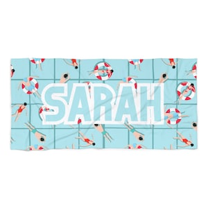 May include: A light blue beach towel with a repeating pattern of people swimming in a pool. The name "SARAH" is printed in white letters across the center of the towel.