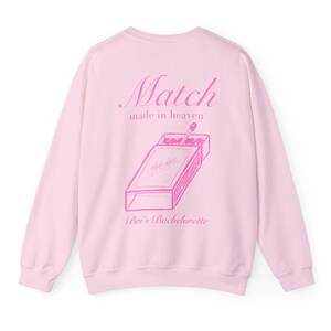 May include: Pink sweatshirt with a graphic of a matchbox and the text "Match made in heaven" and "Bri's Bachelorette" printed on the back.
