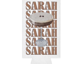 May include: White can cooler with the name "SARAH" repeated five times in brown text. A brown and white cocktail glass with a brown drink and two white dots is in the center of the cooler.