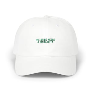 May include: White baseball cap with green embroidered text that reads "The Bride Needs A Margarita".