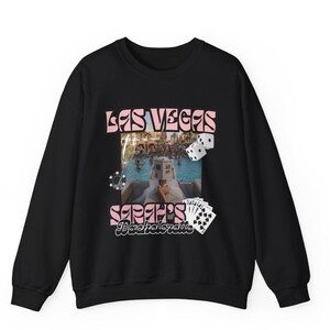 May include: Black sweatshirt with a pink and white graphic that says "LAS VEGAS" and "Sarah's Bachelorette". The graphic includes dice, playing cards, and a photo of a pool party.