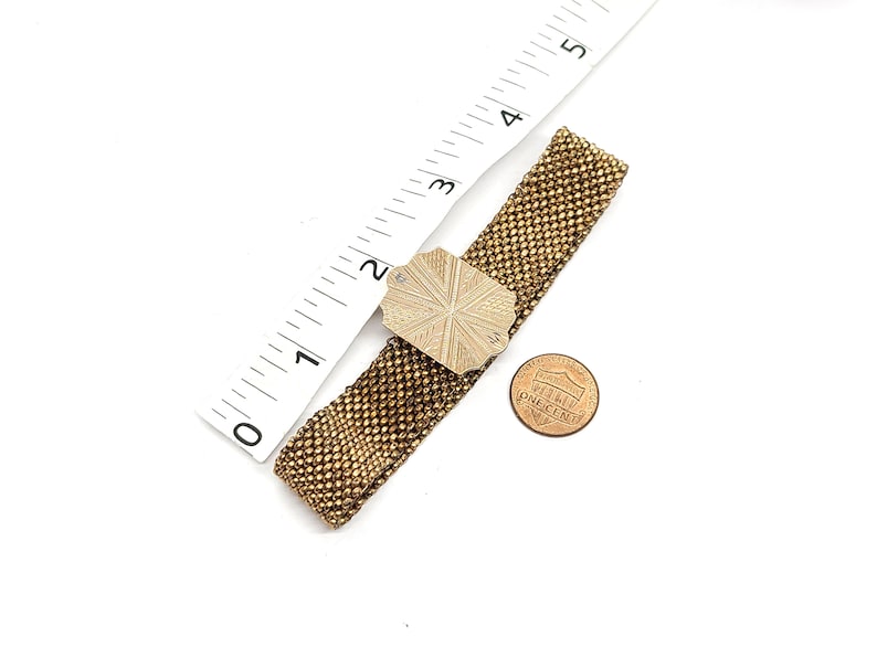May include: A gold chain bracelet with a decorative silver clasp. The clasp is a square shape with a starburst design.