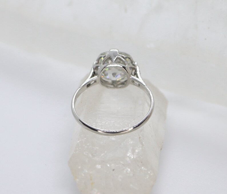 May include: A silver ring with a large, round, clear stone set in a delicate, filigree design.