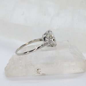 May include: A silver engagement ring with a large, round, clear center stone and smaller stones set in a delicate band.