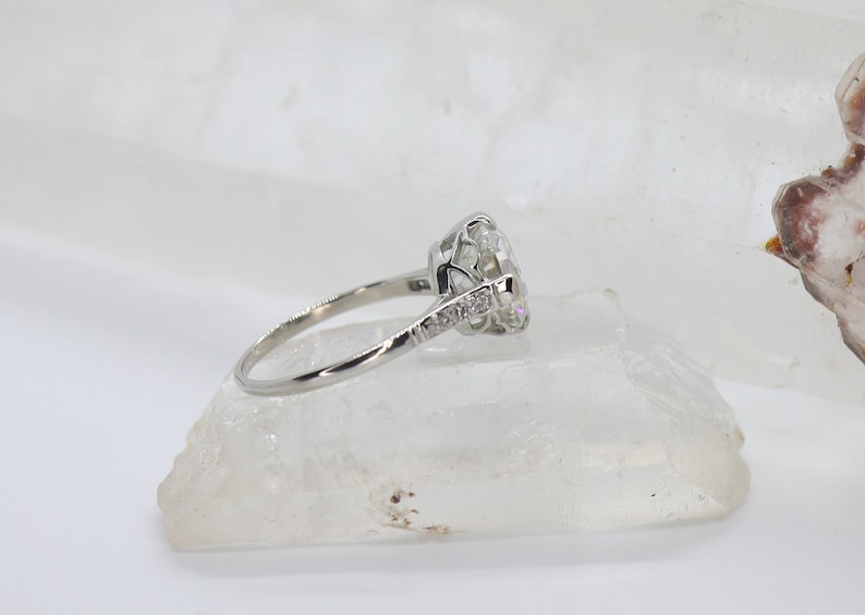 May include: A silver engagement ring with a large, round, clear center stone and smaller stones set in a delicate band.