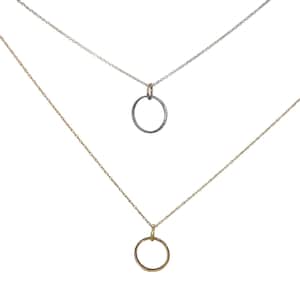 Puede incluir: Dos delicados collares con colgantes circulares. Uno tiene una cadena plateada con un colgante gris oscuro, el otro una cadena dorada y un colgante dorado. Ambos colgantes son círculos abiertos simples.