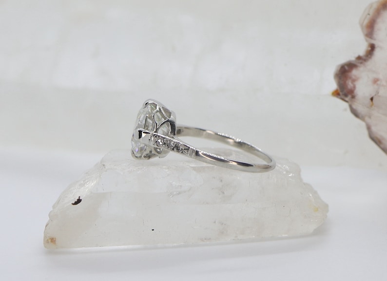 May include: A silver engagement ring with a large, round, clear center stone and smaller stones set in the band.