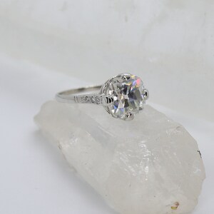 May include: A silver engagement ring with a large, round, clear diamond center stone and smaller diamonds on the band.
