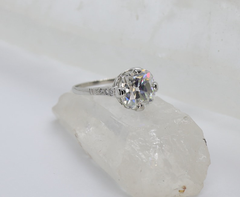 May include: A silver engagement ring with a large, round, clear diamond center stone and smaller diamonds on the band.