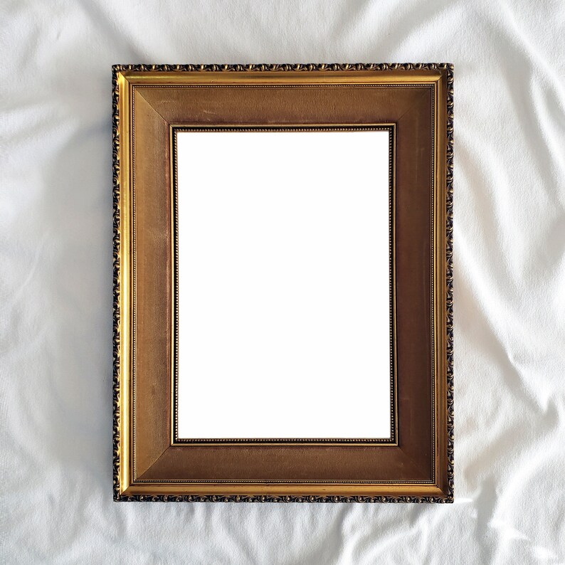 May include: A gold-colored picture frame with a decorative border. The frame is empty and ready for a photo or artwork.