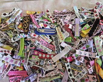 May include: A large collection of colorful hair clips and ribbons. The clips are made of metal and plastic and feature various designs, including polka dots, stripes, and floral patterns. The ribbons are made of satin and come in a variety of colors and widths.