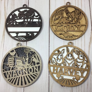 May include: Four round wooden ornaments with cut-out designs. One features a donkey, another horses, a third a tractor, and the last three rabbits. Each has a name cut out: Cody, Wagnon, and Harvey. All have a small hole for hanging.