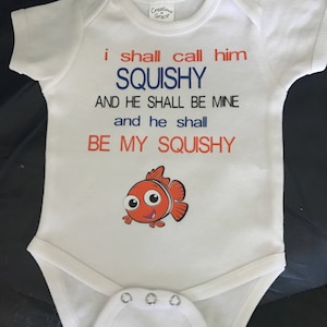 May include: White baby onesie with the text "i shall call him SQUISHY AND HE SHALL BE MINE and he shall BE MY SQUISHY". A cartoon orange and white fish is printed below the text.