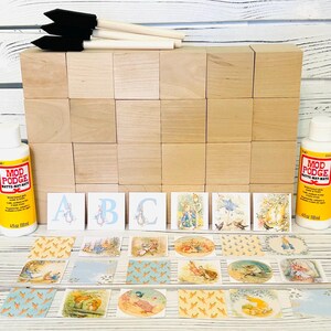 May include: A set of wooden blocks with alphabet letters and images from the Peter Rabbit book series. The set includes two bottles of Mod Podge matte-finish decoupage medium, paintbrushes, and a variety of decorative paper squares.