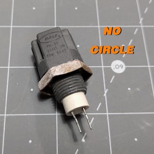以下が含まれることがあります： 「BALF'S PH-25 15KΩ 35° 15W 6825」と印刷された灰色の電気部品。部品の下部から2本の金属製のピンが突き出ています。