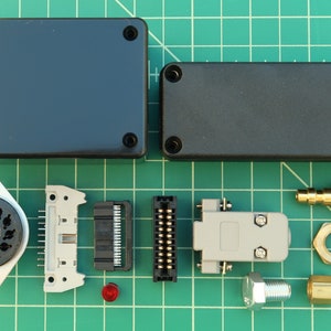 May include: Assortment of electronic components including two black plastic boxes, a gray connector, a black connector, a white connector, a black and white connector, a black and white rotary switch, a red LED, a gold-colored connector, a gold-colored nut, a gold-colored fitting, and a silver-colored fitting.