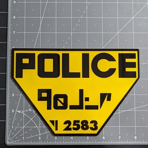 Peut inclure: Un panneau de police jaune et noir avec le mot "POLICE" en grandes lettres noires et le texte "90_1_7" et "1 2583" en lettres noires plus petites.