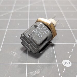 May include: A gray and black electrical component with a gold connector. The component has the text "DALL" and "18K&Omega; 25W 049" printed on it.