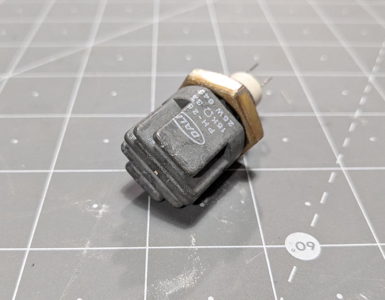 May include: A gray and black electrical component with a gold connector. The component has the text "DALL" and "18K&Omega; 25W 049" printed on it.
