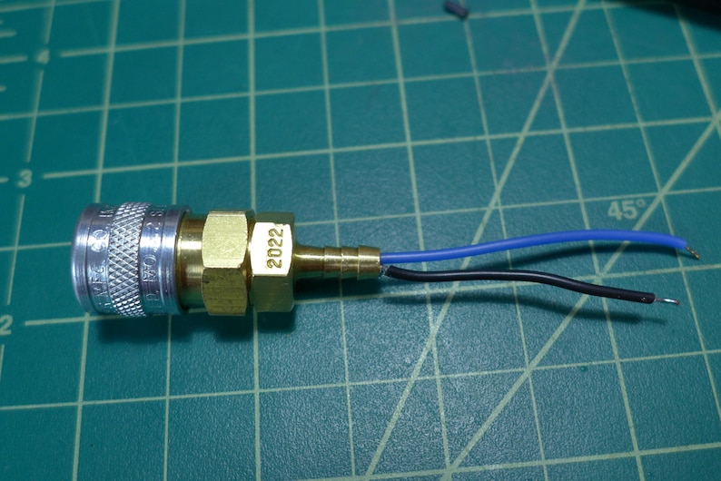 May include: A brass air fitting with a silver threaded connector and a blue and black wire attached. The fitting is labeled "2022".