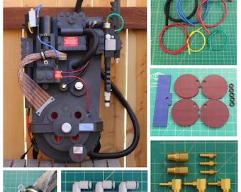 May include: A black and gray Ghostbusters proton pack replica with a variety of wires and hoses. The pack is sitting on a wooden surface. The image also includes close-up shots of various parts and accessories for the pack, including red and black tubing, gold-colored connectors, and white plastic connectors.