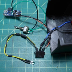 May include: A close-up of a circuit board with wires connected to a switch, a potentiometer, and a connector. The wires are color-coded with black, red, green, blue, and yellow.
