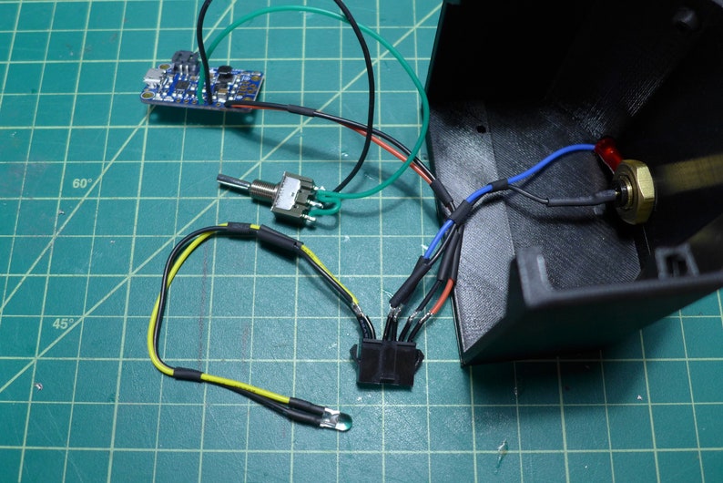 May include: A close-up of a circuit board with wires connected to a switch, a potentiometer, and a connector. The wires are color-coded with black, red, green, blue, and yellow.
