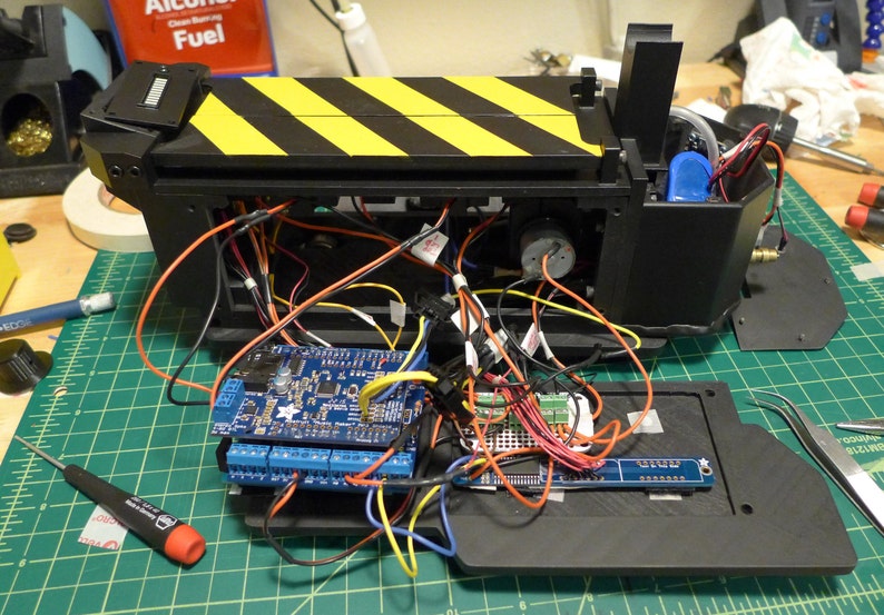 May include: A close-up of a black and yellow striped box with wires and a blue circuit board inside. The box is open and the circuit board is visible. There are also some other electronic components inside the box.