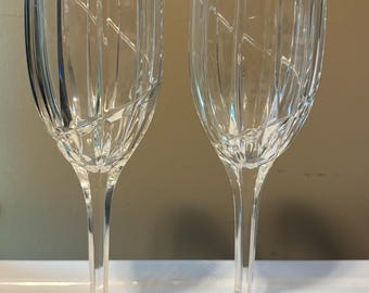 May include: Two clear glass wine glasses with a vertical ribbed pattern. The glasses have a tall stem and a wide base.