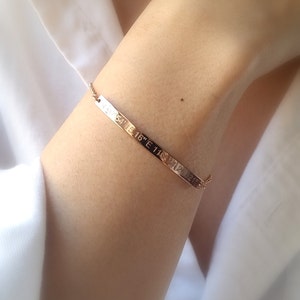 May include: A rose gold bracelet with a thin chain and a flat bar charm engraved with the coordinates "N 54° 15' 16" E 11° 24' 21".
