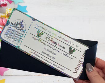 May include: A rectangular Disneyland ticket with a holographic border, featuring a barcode, the text FastPass to Fun, Happy Birthday, To: Paisley Ruby, From: Mom & Dad, and Say Goodbye to Normal and Hello to Magic, partially inserted into a black envelope.