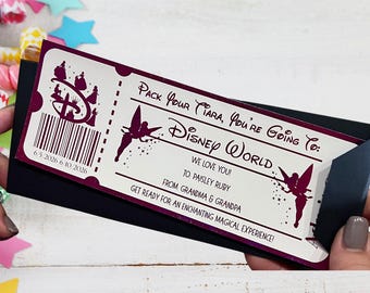 May include: A rectangular Disney World gift ticket in white with dark purple text and graphics. It features silhouettes of Tinker Bell, a barcode, and the text: Pack Your Tiara, You're Going To: Disney World, We Love You! To: Paisley Ruby, From: Grandma & Grandpa, Get Ready For An Enchanting Magical Experience! 6/5/2026 6/10/2026.