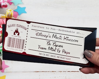 May include: A rectangular paper ticket with a white background and dark red borders. It features the text Magic Kingdom, FastPass to Fun--Redeemable at... Disney's Magic Kingdom, To: Taylor, From: Mimi & Pops, and Time for rides, snacks, and mickey hugs!