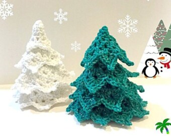 Puede incluir: Dos árboles de Navidad de ganchillo, uno blanco y otro verde turquesa. Los árboles están sobre una superficie blanca.