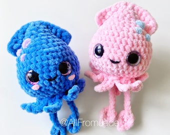 Puede incluir: Dos juguetes de pulpo de ganchillo hechos a mano. Uno es azul, el otro rosa. Ambos tienen ojos grandes y expresivos, pequeñas sonrisas y tentáculos. El pulpo azul tiene detalles morados, mientras que el rosa tiene detalles celeste. Fondo blanco.