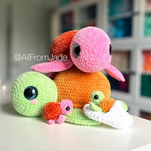 Peut inclure: Quatre jouets en forme de tortues en crochet de différentes couleurs. La plus grande tortue est rose, orange et verte. Les trois autres tortues sont vertes, orange et blanches.