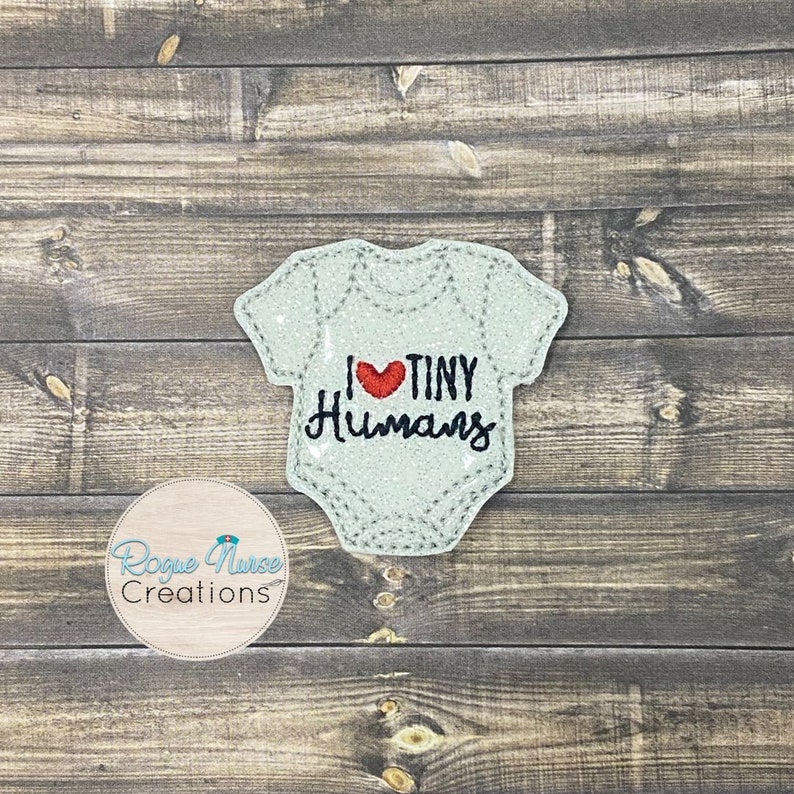 Op de afbeelding: Een lichtblauwe baby romper met een rood hart en de tekst "Ik hou van kleine mensen" geborduurd erop.