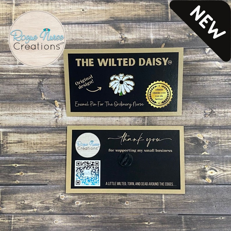 May include: Two cards with gold trim. The top card has a black background with white text that reads "The Wilted Daisy" and "Enamel Pin For The Ordinary Nurse". A white daisy enamel pin is on the card. The bottom card has a black background with white text that reads "Rogue Nurse Creations" and "thank you for supporting my small business". A black and white QR code is on the card. The text "A little wilted, torn, and dead around the edges..." is on the card. The word "NEW" is in a white box with a black outline.