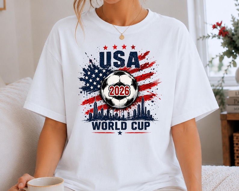 USA Soccer World Cup 2026 graphic shirt featuring soccer ball, American flag splash art, skyline design and patriotic football fan aesthetic