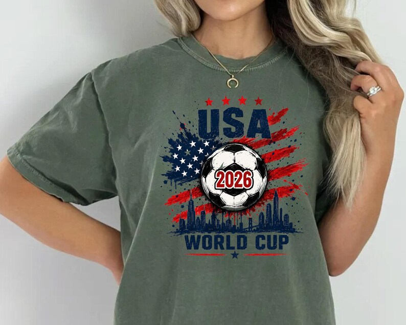 USA Soccer World Cup 2026 graphic shirt featuring soccer ball, American flag splash art, skyline design and patriotic football fan aesthetic