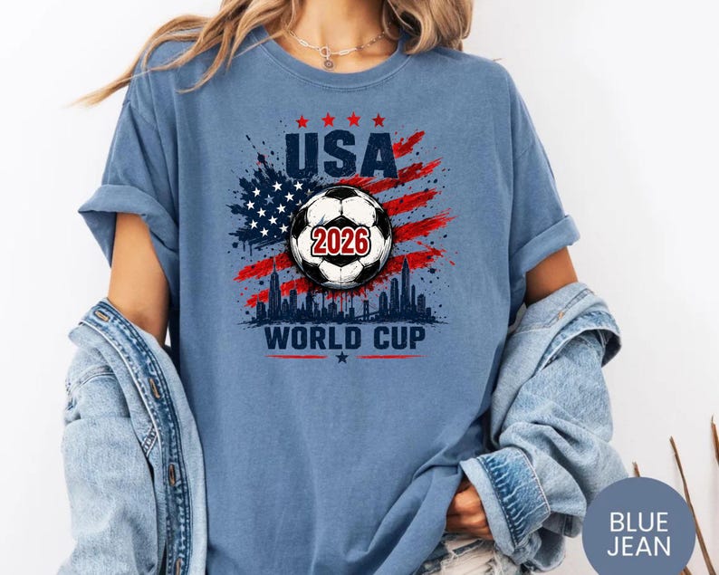 USA Soccer World Cup 2026 graphic shirt featuring soccer ball, American flag splash art, skyline design and patriotic football fan aesthetic