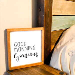 May include: A wooden framed sign with the text "Good Morning Gorgeous" in black script font on a white background.