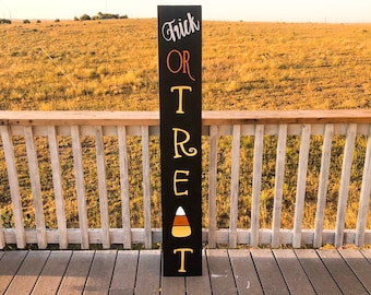 May include: Black wooden sign with the words "Trick or Treat" written in white and yellow letters. A candy corn graphic is in the center of the sign.