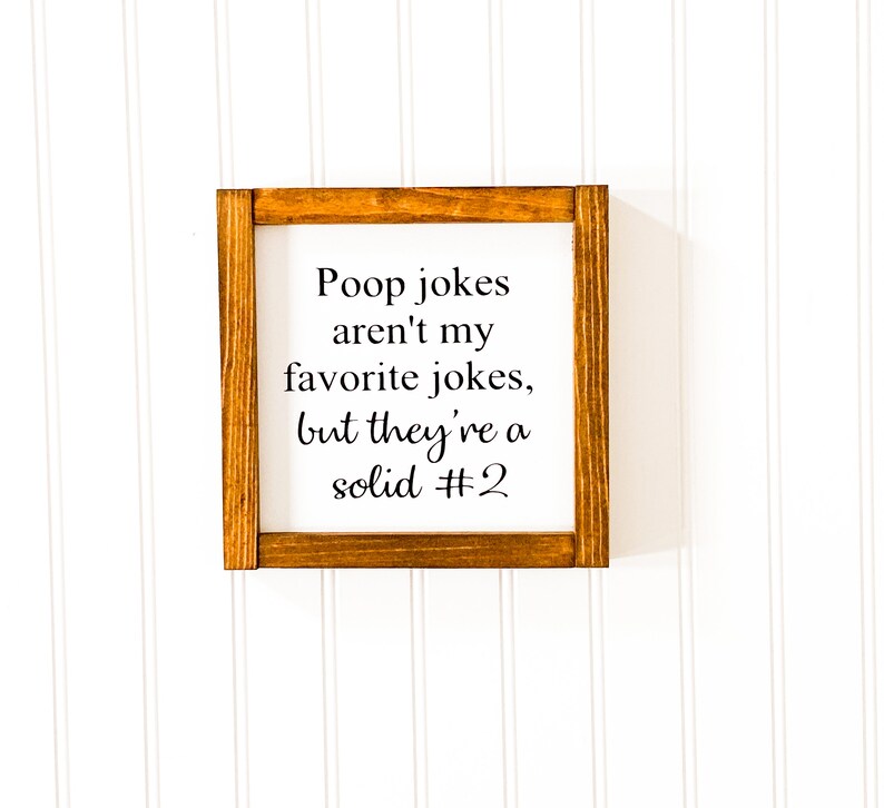 May include: A wooden sign with a brown frame and white background. The sign says "Poop jokes aren't my favorite jokes, but they're a solid #2".