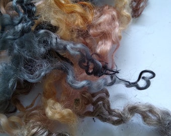 May include: A pile of different colored wool fibers, including gray, brown, and blonde. The fibers are soft and fluffy, and they are perfect for spinning or felting.
