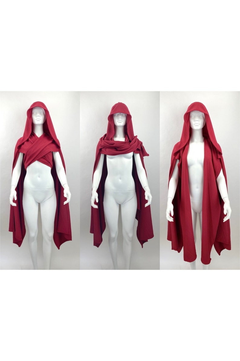 May include: A red hooded cape with a long, flowing design. The cape can be worn in three different ways, as shown in the image.