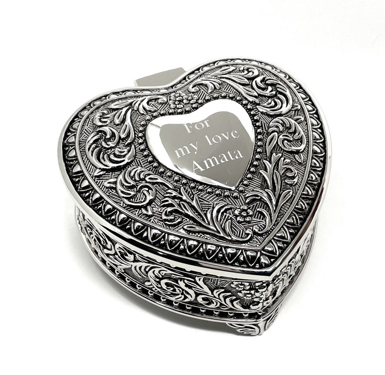 May include: Silver heart-shaped trinket box with an ornate design and an engraved message that reads "For my love Amata".