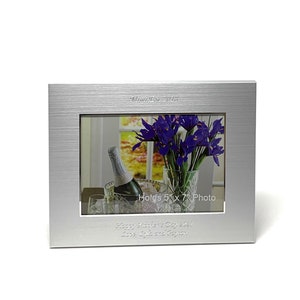 May include: Silver photo frame with a brushed finish. The frame holds a 5 x 7 inch photo and has the text "Happy Mother's Day 2021 Love, Luke and Peyton" engraved on the bottom.